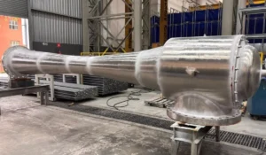 Tubo industrial de metal grande em ambiente de fábrica, que representa um sistema de vácuo em artigo da Apema.