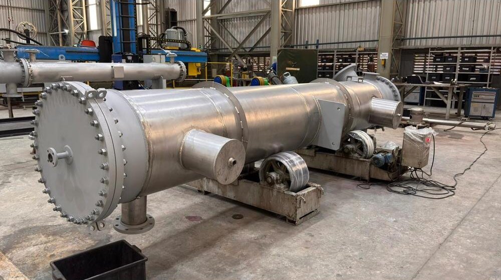 Trocador de Calor Casco e Tubo azul sobre uma mesa branca e fundo de tecido branco.